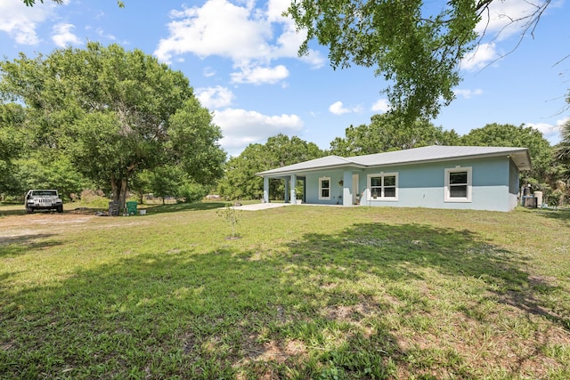 7633 NW 93rd Ct, Okeechobee, FL 34972 - back of house featuring stucco siding, metal roof, and a yard