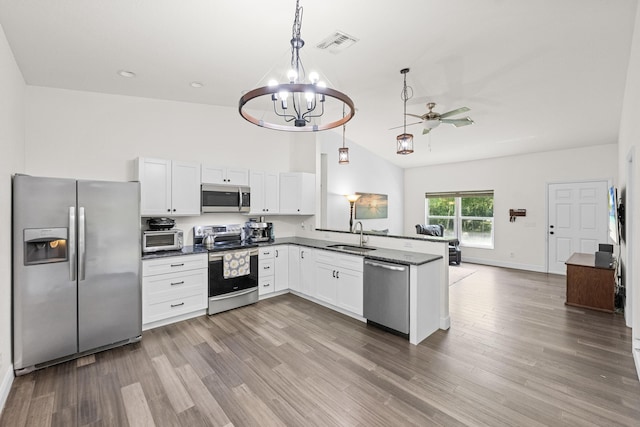 7633 NW 93rd Ct, Okeechobee, FL 34972 - kitchen with stainless steel appliances, dark countertops, white cabinets, a peninsula, and wood finished floors