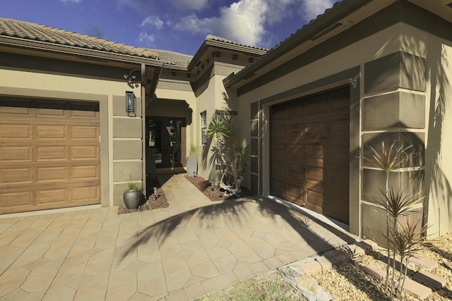 exterior space featuring a garage, stucco siding, decorative driveway, and a tile roof