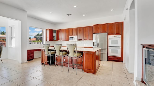 kitchen featuring white appliances, a breakfast bar, light countertops, backsplash, and visible vents
