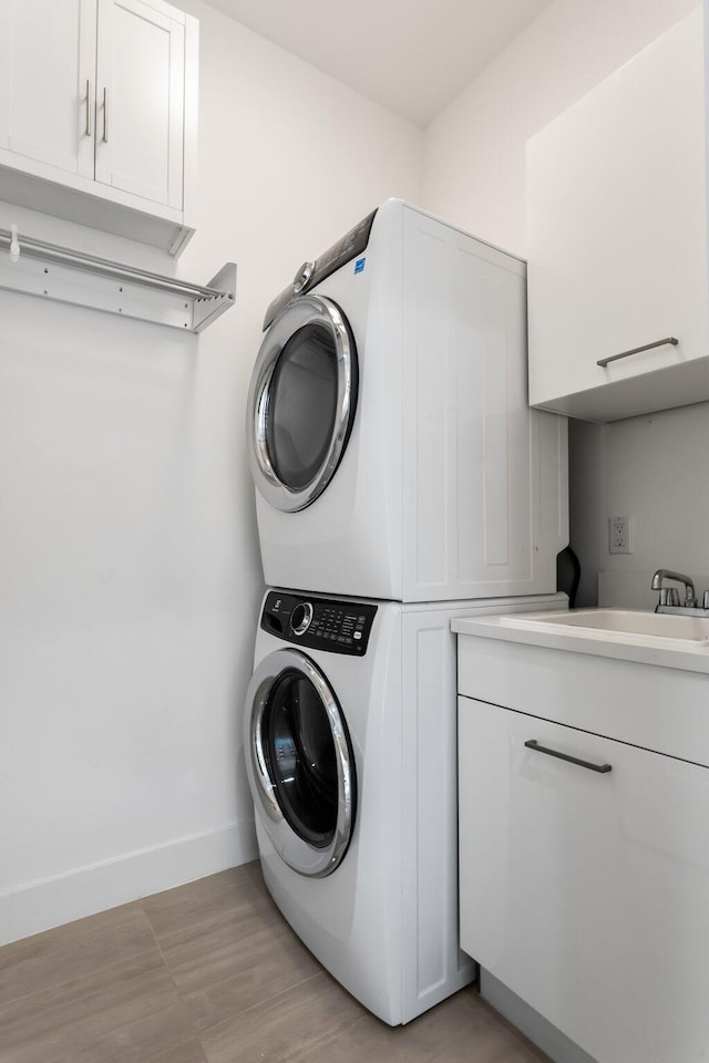 4240 NW 17th Ave, Boca Raton, FL 33431 - clothes washing area featuring stacked washer / dryer, cabinet space, baseboards, and light wood-type flooring