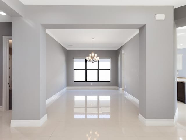 spare room with light tile patterned floors, baseboards, and a notable chandelier