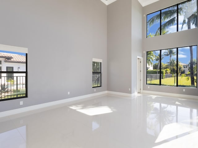 spare room with baseboards, a high ceiling, and tile patterned flooring