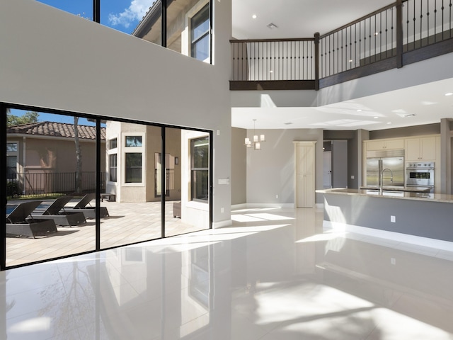 interior space featuring recessed lighting, marble finish floor, a high ceiling, and an inviting chandelier