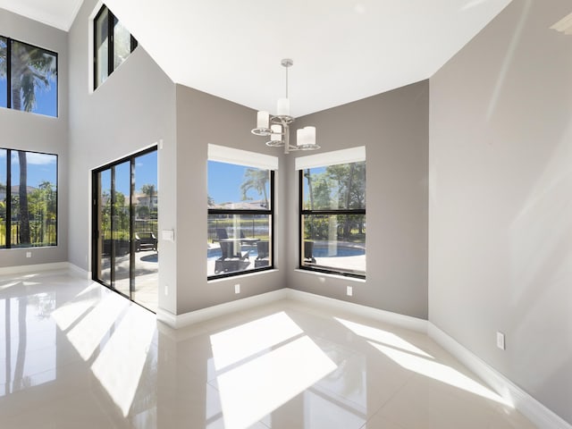 empty room featuring baseboards, an inviting chandelier, and a towering ceiling