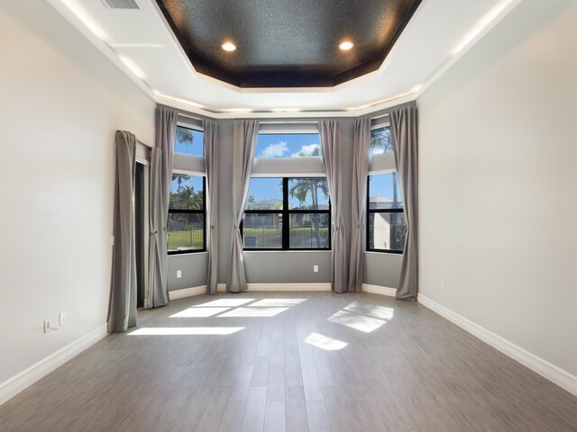 spare room featuring visible vents, baseboards, a tray ceiling, recessed lighting, and wood finished floors