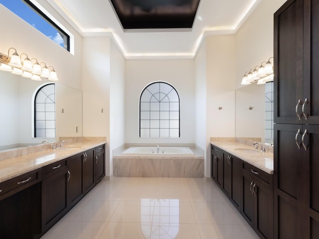 full bath featuring two vanities, tile patterned floors, a bath, and a sink