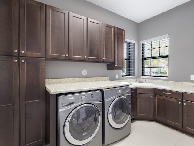 laundry room with a sink, light tile patterned flooring, cabinet space, and washer and clothes dryer