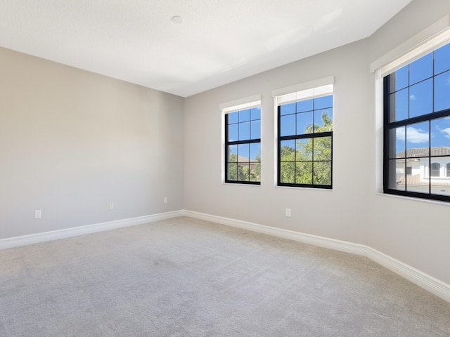 unfurnished room with baseboards and light carpet
