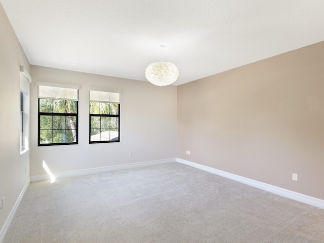 unfurnished room featuring a textured ceiling, baseboards, and light carpet