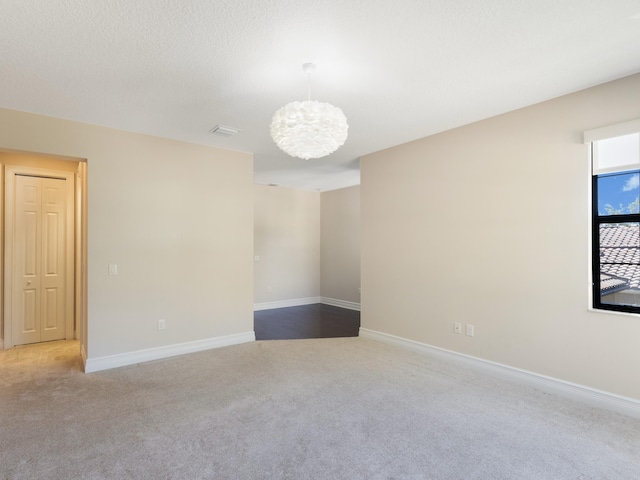 unfurnished room with baseboards, carpet floors, a notable chandelier, and visible vents