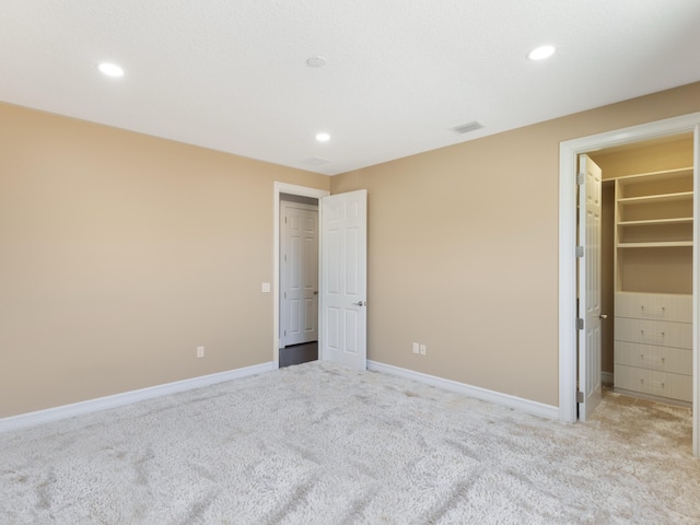 unfurnished bedroom with a spacious closet, recessed lighting, and baseboards