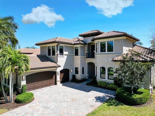 mediterranean / spanish house with stucco siding, decorative driveway, and a tiled roof
