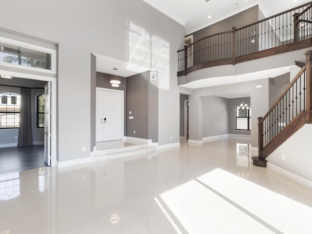 unfurnished living room featuring a wealth of natural light, baseboards, and a towering ceiling
