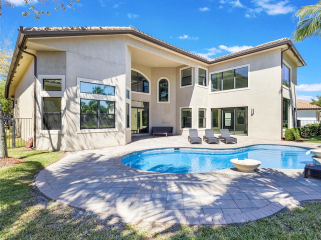 rear view of house featuring fence, a fenced in pool, stucco siding, a tile roof, and a patio area