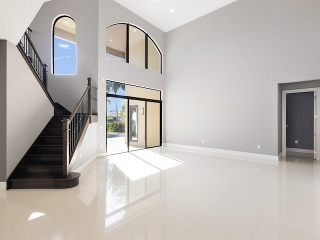 unfurnished living room featuring baseboards, stairs, a towering ceiling, crown molding, and tile patterned floors