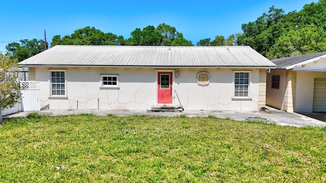 view of front of property featuring stucco siding, metal roof, fence, and a front lawn