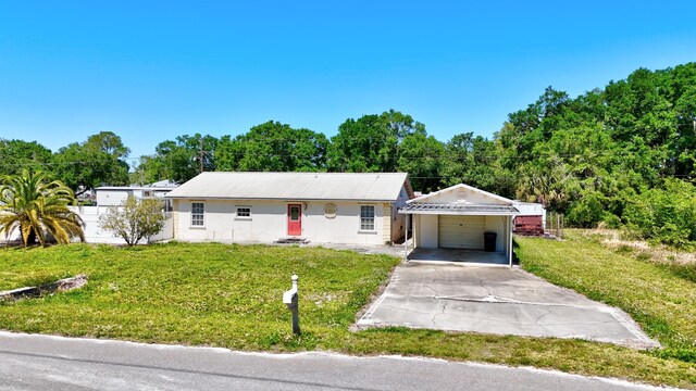 ranch-style house with a detached garage, driveway, fence, and a front lawn