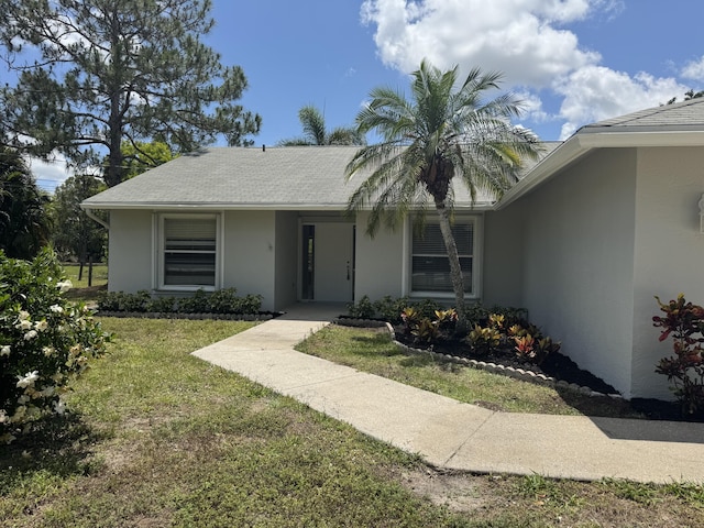 view of front of property with stucco siding and a front lawn