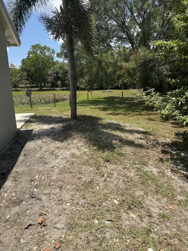 view of green lawn with view of wooded area