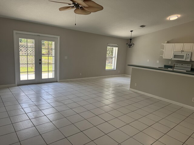 unfurnished living room with a ceiling fan, french doors, a textured ceiling, and baseboards