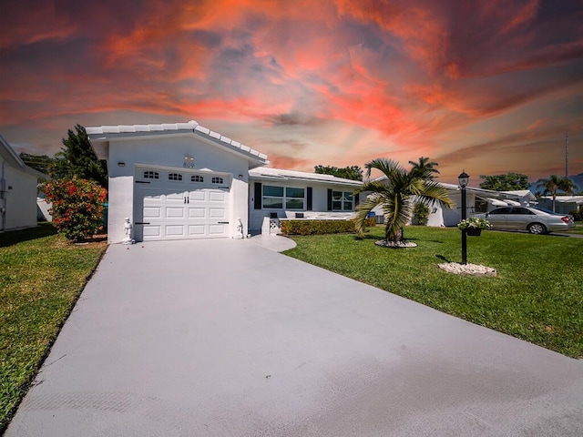 ranch-style house with stucco siding, concrete driveway, an attached garage, and a front lawn