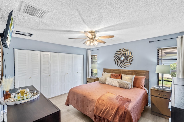 bedroom with light wood-style flooring, visible vents, a closet, and ceiling fan