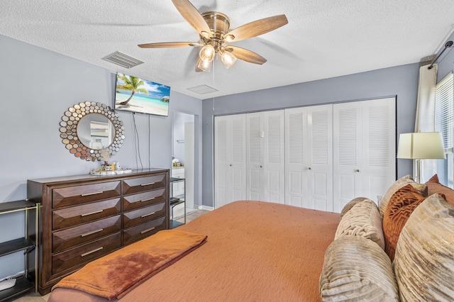 bedroom with a closet, visible vents, a textured ceiling, and ceiling fan