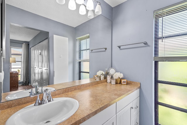 bathroom with a textured ceiling, a chandelier, and vanity