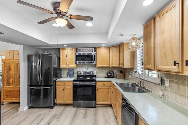 kitchen featuring a sink, a tray ceiling, light wood-style floors, and black appliances