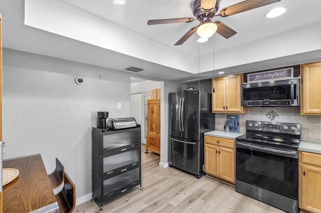 kitchen featuring tasteful backsplash, stainless steel microwave, range with electric stovetop, and freestanding refrigerator
