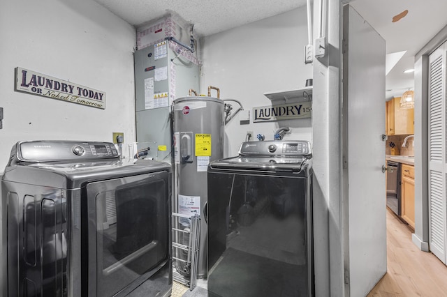 clothes washing area featuring laundry area, a sink, light wood-style floors, electric water heater, and independent washer and dryer