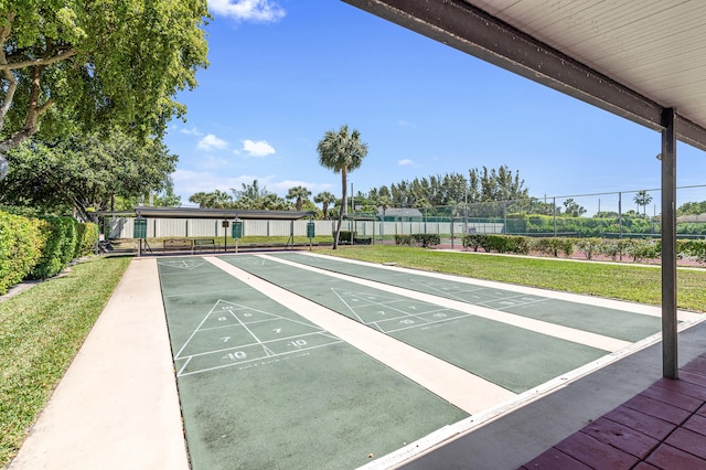 surrounding community featuring a lawn, shuffleboard, and fence