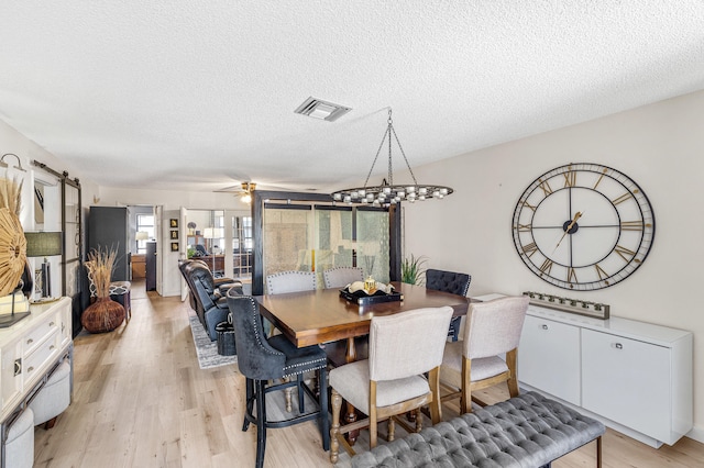 dining space with light wood finished floors, visible vents, and a textured ceiling