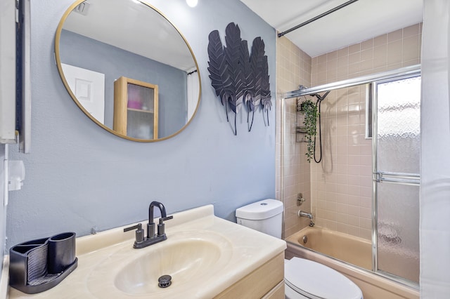 bathroom featuring enclosed tub / shower combo, toilet, and vanity