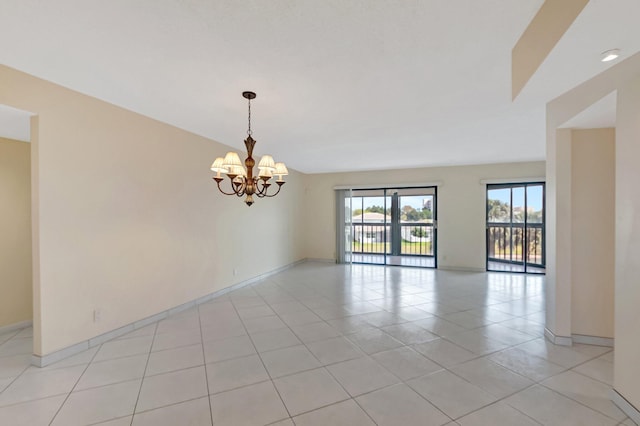 unfurnished room with baseboards, light tile patterned floors, and a chandelier