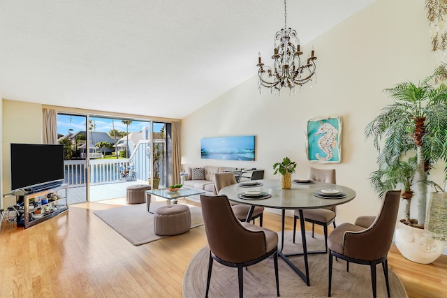 213 Ocean Dunes Cir, Jupiter, FL 33477 - dining room featuring a textured ceiling, wood finished floors, an inviting chandelier, expansive windows, and vaulted ceiling