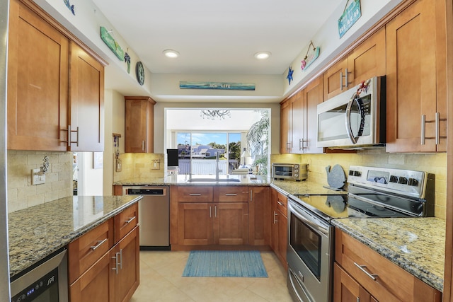213 Ocean Dunes Cir, Jupiter, FL 33477 - kitchen featuring a sink, brown cabinetry, appliances with stainless steel finishes, and light stone counters