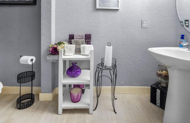 bathroom with a sink, wood finished floors, and a textured wall