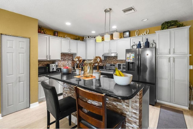 kitchen with under cabinet range hood, visible vents, appliances with stainless steel finishes, and light wood-style floors