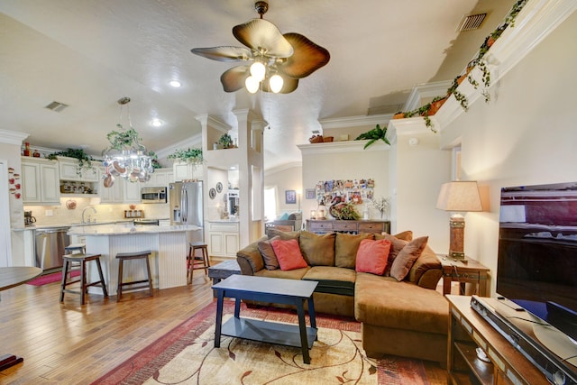 12693 Coral Breeze Dr, Wellington, FL 33414 - living area with light wood-style flooring, ceiling fan with notable chandelier, visible vents, and ornamental molding