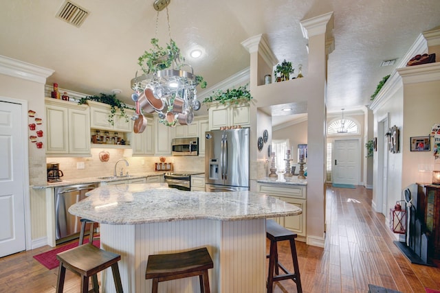 12693 Coral Breeze Dr, Wellington, FL 33414 - kitchen featuring visible vents, a breakfast bar, ornamental molding, wood finished floors, and appliances with stainless steel finishes