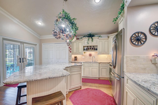 12693 Coral Breeze Dr, Wellington, FL 33414 - kitchen with freestanding refrigerator, a kitchen bar, crown molding, light wood-type flooring, and backsplash