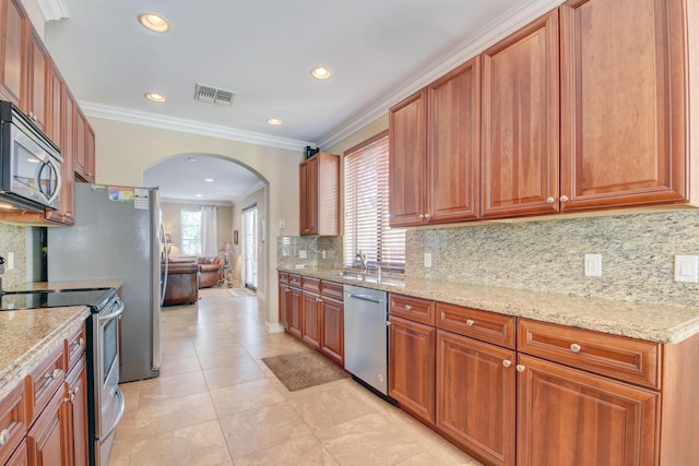 kitchen featuring visible vents, ornamental molding, a wealth of natural light, appliances with stainless steel finishes, and arched walkways