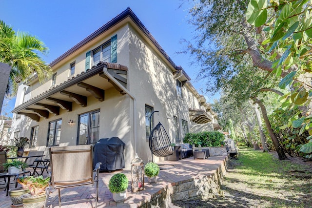 back of house with stucco siding and a patio