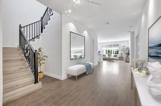 hall with stairs, visible vents, baseboards, and wood finished floors