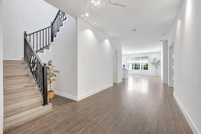 corridor featuring visible vents, baseboards, and wood finished floors
