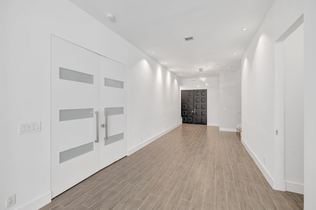 hall with recessed lighting, light wood-style flooring, baseboards, and visible vents