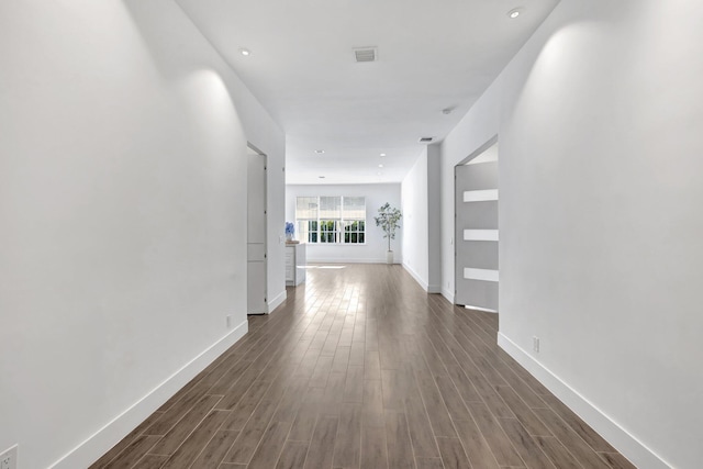 hall featuring visible vents, dark wood-style flooring, and baseboards