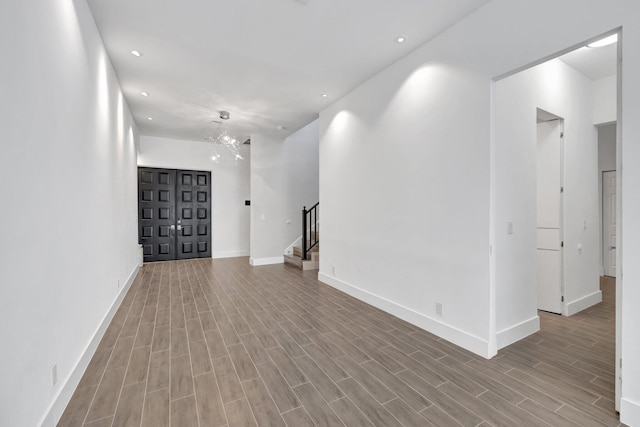 unfurnished room featuring recessed lighting, stairway, wood finished floors, baseboards, and a notable chandelier